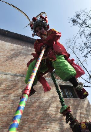 A child performer sits on a supporting pole before she is carried high on the shoulders of an elder during a local folk parade for the lantern festival celebration at a village in Luoyang City, central China's Henan Province, Feb. 9, 2009.