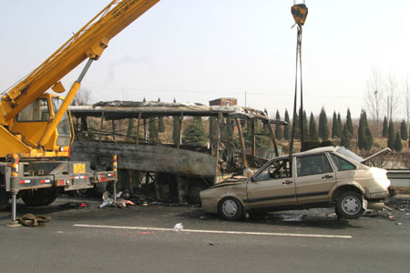 Rescue workers use a crane to move a damaged vehicle at the site of a traffic accident caused by heavy fog on the segment of Jingfu Highway in Tai'an City of east China's Shandong province, Feb. 10, 2009. More than 100 vehicles collided into each other due to heavy fog on Tuesday morning, which caused some passengers injured. (Xinhua/Gong Hui)