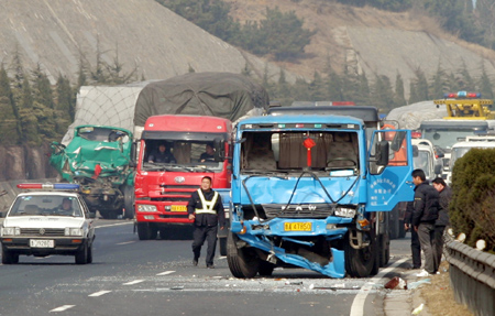 Traffic policemen and drivers check out damaged vehicles at the site of a traffic accident caused by heavy fog on the segment of Jingfu Highway in Tai'an City of east China's Shandong province, Feb. 10, 2009. More than 100 vehicles collided into each other due to heavy fog on Tuesday morning, which caused some passengers injured. (Xinhua/Gong Hui)