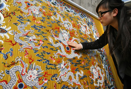 A working staff touches a piece of Chinese brocade decorated with some 180,000 pearls, each 1.3mm in diameter, at Suzhou City in east China's Jiangsu Province, Feb. 10, 2009. 