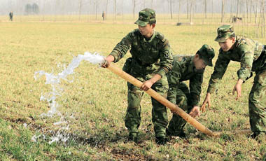Soldiers irrigate a field in Shangqiu City, Henan Province, with water carried to the site by a tanker yesterday. About 533,600 hectares of wheat in Shangqiu have been hit by drought. Soldiers have been drafted in to help farmers cope. [Xinhua]
