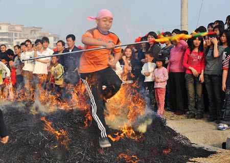 A boy jumps over bonfire in Xidong Village of Zhanlong Township in Puning City, south China's Guangdong Province, Feb. 10, 2009. As a local folk custom, the villagers here light the bonfire outdoor for people to leap over, which represents the passing of the year and entering in the new year. [Ma Ka/Xinhua]