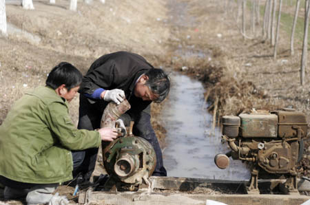Farmers fix water pump in Fuchun Township in Heze City, east China's Shandong Province, Feb. 10, 2009. Thirty floodgates are opened in Shandong Province to draw water from the Yellow River to irrigate the wheat fields in fighting against the drought and reducing damages. [Zhang Xiaoli/Xinhua]