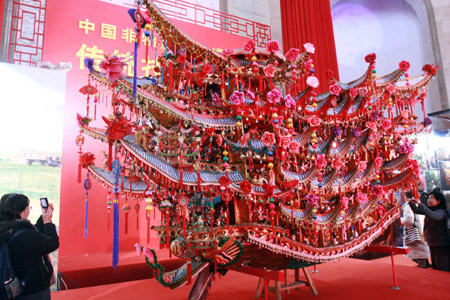 A Chinese takes pictures for a dragon-boat-shaped lamp from east China's Zhejiang Province at an exhibition intending to showcase the country's progress in protecting intangible cultural items in Beijing, capital of China, Feb. 10, 2009. (Xinhua/Chen Xiaogen)