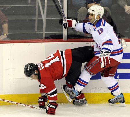 New York Rangers center Scott Gomez (19) sends New Jersey Devils winger Brian Gionta (14) to the ice along the boards in the first period of their NHL hockey game in Newark, New Jersey, February 9, 2009. 