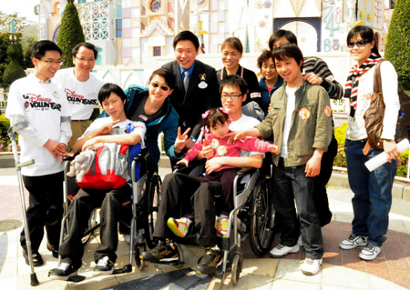 Youngsters who were crippled in the 5.12 massive earthquake in southwest China's Sichuan Province and their families pose for a group photo with employees at the Disneyland in Hong Kong, China, on Feb. 10, 2009. 