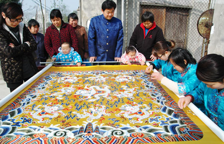Craftswomen put finishing touches for a piece of Chinese brocade decorated with some 180,000 pearls, each 1.3mm in diameter, at Suzhou City in east China's Jiangsu Province, Feb. 10, 2009. 