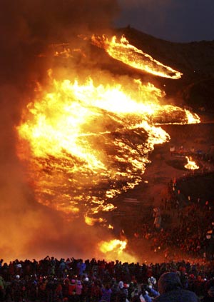 People look at burning pampas grass at Hwawang mountain in Changnyeong, about 275 km (170 miles) southeast of Seoul, February 9, 2009, in celebration of 'Jeongwol Daeboreum', or Great Full Moon, which is a Korean traditional holiday that celebrates the first full moon of the lunar calendar. 