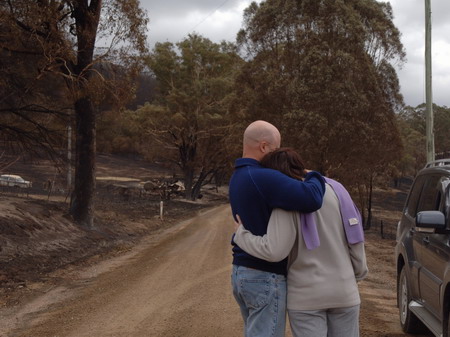 A couple hugs in front of their burnt house in a town near Melbourne February 11, 2008. [Xinhua] 