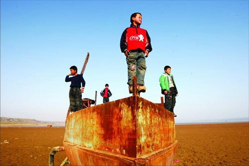 The water level in Luhun reservoir, the second largest reservoir in the central China's Henan province, has quickly fallen, leaving some boats lying exposed on the bottom of the dry dam. Children are attracted to these boats, regarding them as their new playground toys. [Southern Metropolis Daily] 