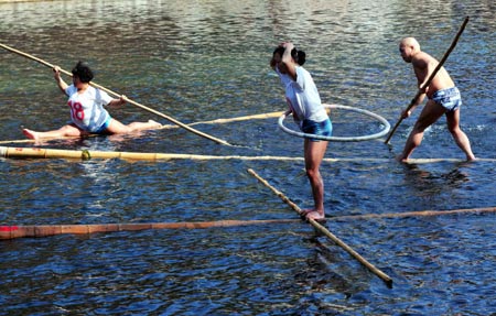 A woman play Hula Hoop while others pose in different gestures on the floating bamboo sticks on Huaxi River in Guiyang, capital of southwest China's Guizhou Province, Feb. 11, 2009. [Qin Gang/Xinhua]