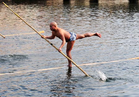 A man stands on one foot on a floating bamboo stick on Huaxi River in Guiyang, capital of southwest China's Guizhou Province, Feb. 11, 2009. [Qin Gang/Xinhua]