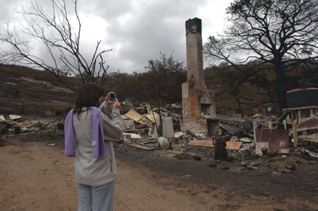 A woman takes photos for the ruins damaged by the bushfire on a farm, 50km to the north of Melbourne, Victoria state, Australia, Feb. 11, 2009. Fire continued to ravage across southern Australia Tuesday, threatening local communities and killing at least 181 so far. More than 900 homes were destroyed in the blaze, making it the country's worst bushfire disaster in history.(Xinhua/Jiang Yaping)