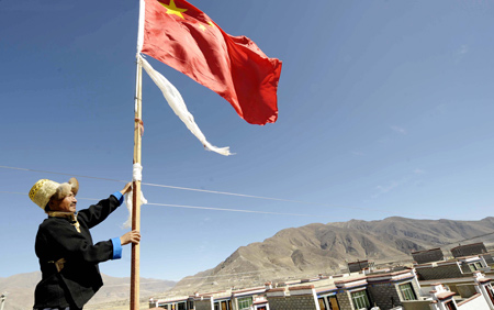 A Tibetan villager fixes a flagstaff with Chinese national flag next to his new house in Kunggar Town of Maizhokunggar County in Lhasa, capital of southwest China's Tibet Autonomous Region, Feb. 11, 2009.