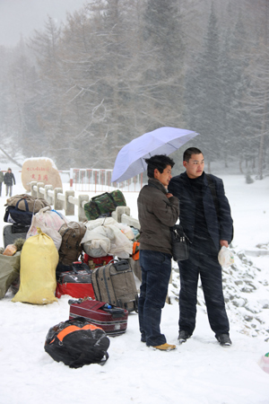 Two men wait for coach in the snow in Hami, northwest China's Xinjiang Ugyur Autonomous Region, Feb. 11, 2009. The light to moderate snow fall hit the north Hami along the Tianshan Mountains which relieved the drought in Barkol Grassland. (Xinhua/Zhu Zhenghua)