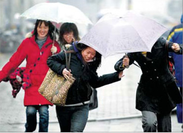A drizzle brings smile on pedestrians' faces as they walk on a Beijing street yeaterday. The city experienced its first rain after 110 days, the longest in 38 years. [Wang Jing/China Daily] 