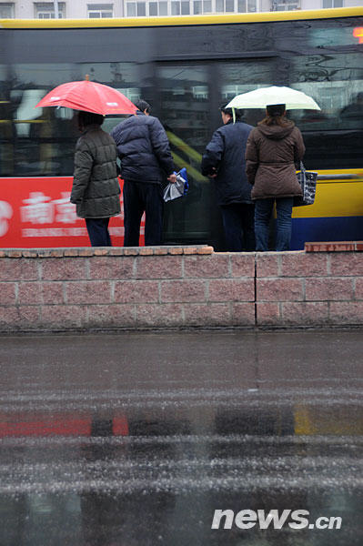 Local people wait for the bus in a light rain which is the first after 111 days of no precipitation in Beijing on Thursday, February 12, 2009. [Xinhua] 