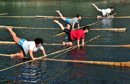 People pose in different gestures on floating bamboo sticks on the Huaxi River in Guiyang, capital of southwest China&apos;s Guizhou Province, Feb. 11, 2009. The splendid performances have attracted so many tourists. (Xinhua/Qin Gang)