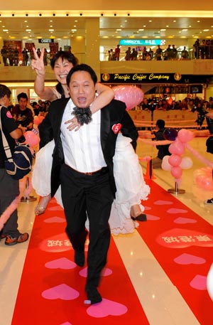 A man carrying his wife rushes to the final during a competition to celebrate the valentine's day, which falls on Feb. 14, at a shopping mall in Hong Kong, south China, Feb. 12, 2009. (Xinhua/Chen Duo)