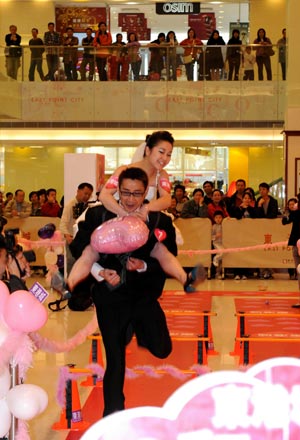 A man carrying his wife rushes to the final during a competition to celebrate the valentine's day, which falls on Feb. 14, at a shopping mall in Hong Kong, south China, Feb. 12, 2009. (Xinhua/Chen Duo)