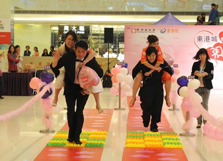 Men carrying their wives rush to the final during a competition to celebrate the valentine's day, which falls on Feb. 14, at a shopping mall in Hong Kong, south China, Feb. 12, 2009. (Xinhua/Chen Duo)