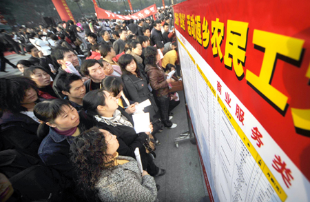 Migrant workers check job information on a job fair in Yichang, central China's Hubei Province, Feb. 12, 2009.