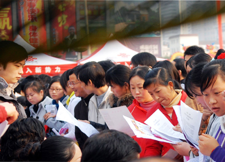 Migrant workers consult on a job fair in Yichang, central China's Hubei Province, Feb. 12, 2009