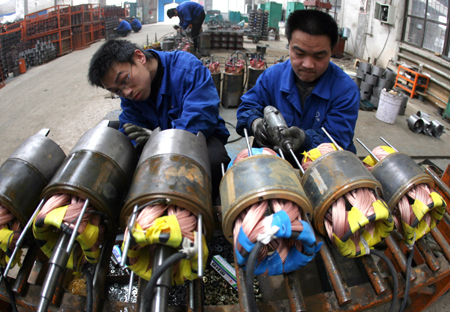 Workers fix electric pump machines in the workshop of a pump company in Yuncheng, north China's Shanxi Province, Feb. 12, 2009.