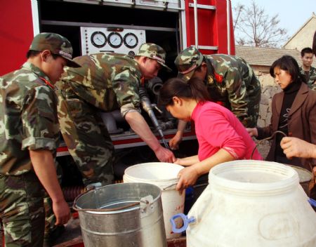 Soldiers help the villagers to get water from a fire engine in Lieshan Township in Huaibei City, east China&apos;s Anhui Province, Feb. 12, 2009. Fire engines were sent to deliver water for residents in the villages of Lieshan Township. Huaibei city has suffered from drought since October last year. (Xinhua/Wan Shanchao)(