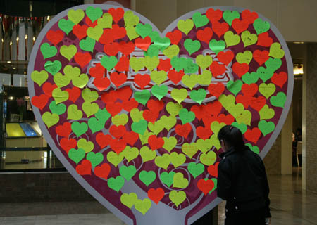 A customer reads memos with wishes sticked on a wall decorated for the upcoming Valentine&apos;s Day at a mall in Beijing, Feb. 13, 2009. (Xinhua/Xing Guangli)