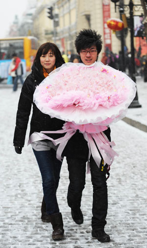 A couple of lovers walk with a bouquet of roses in Harbin, capital of northeast China's Heilongjiang Province, Feb. 14, 2009. Lots of lovers bought roses to celebrate the Valentine's Day. [Xinhua] 
