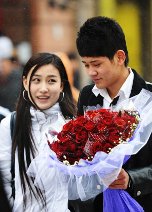 A couple of lovers walk with a bouquet of roses in Harbin, capital of northeast China's Heilongjiang Province, Feb. 14, 2009. Lots of lovers bought roses to celebrate the Valentine's Day. [Xinhua] 