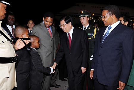 Chinese President Hu Jintao (2nd R, front), who is greeted by Tanzanian President Jakaya Mrisho Kikwete (1st R, front), shakes hands with a child upon his arrival at the airport in Dar es Salaam, Tanzania, Feb. 14, 2009. Hu arrived here on Saturday night for a state visit to Tanzania. [Xinhua]