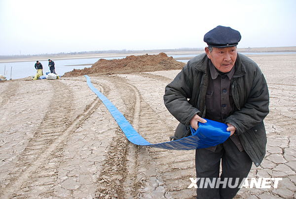 Villagers in Tangyin County, Henan province, channel water into their wheat field on February 15, 2009.