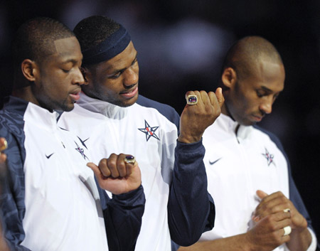 Cleveland Cavaliers' LeBron James (C), Miami Heat's Dwyane Wade (L) and Los Angeles Lakers' Kobe Bryant look at their rings during a ceremony where they were presented rings for wining the gold medal at the Olympics in Beijing of China last year, during halftime at the NBA All-Star basketball game in Phoenix, Arizona of the United States, Feb. 15, 2009. [Xinhua]