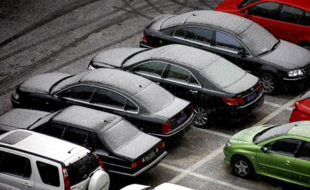 Cars covered by snow park alongside a road in Beijing, capital of China, Feb. 17, 2009. [Xinhua]