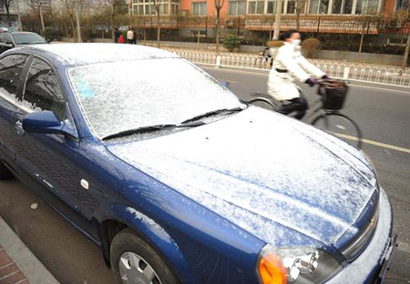 A car covered by snow is seen alongside a road in Beijing, capital of China, Feb. 17, 2009. [Xinhua] 