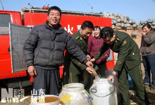 Photo taken on February 15, 2009 shows soldiers and policemen help the villagers to get water from a fire engine in Xinzhuang Township, Zhaoyuan City, Shandong Province. Fire engines were sent to deliver water for residents in the villages of Xinzhuang Township.