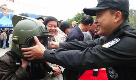 A Chinese police officer helps a local resident to try a helmet during a city show at a square in Liuzhou, southwest China's Guangxi Zhuang Autonomous Region, Feb. 17, 2009. [Li Bin/Xinhua] 