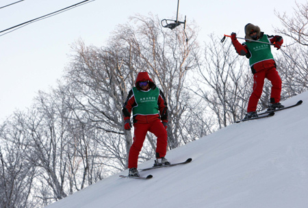 Workers check the snow track of Yabuli Ski Resort, 195km southeast away from Harbin City, capital of northeast China's Heilongjiang Province, Feb 17, 2009.[Meng Yongmin/Xinhua]