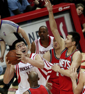  Houston Rockets center Yao Ming (L) is defended by New Jersey Nets forward Yi Jianlian (R) as he goes up for a shot during their NBA basketball game in Houston February 17, 2009. [Xinhua/Reuters] 