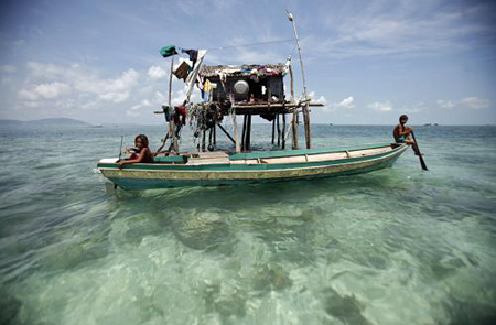  Young sea gypsies sit on their boat outside of their family hut in their neighbourhood in Sulawesi Sea in Malaysia's state of Sabah on the Borneo island February 17, 2009.[Xinhua/Reuters]