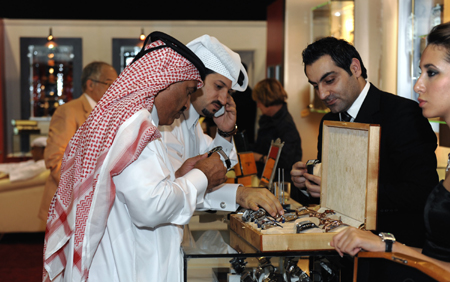 Two Qatar men select watches during the 6th Doha Jewellery and Watch Exhibition in Doha, capital of Qatar, Feb. 17, 2009. [Chen Shaojin/Xinhua]