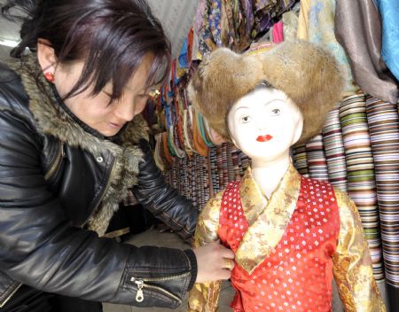 A shopowner shows a traditional children's clothes of Tibetan ethnic group at her shop in Lhasa, capital of southwest China's Tibet Autonomous Region, on Feb. 18, 2009. Traditional clothes of Tibetan ethnic group are popular among people of Tibetan ethnic group as Tibetan New Year, which falls on Feb. 25 this year, is coming.[Purbu Zhaxi/Xinhua] 