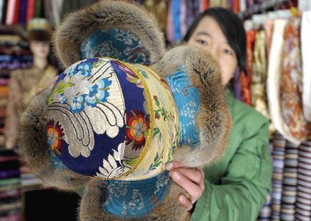 A shopowner shows a traditional hat of Tibetan ethnic group at her shop in Lhasa, capital of southwest China's Tibet Autonomous Region, on Feb. 18, 2009. Traditional clothes of Tibetan ethnic group are popular among people of Tibetan ethnic group as Tibetan New Year, which falls on Feb. 25 this year, is coming. [Purbu Zhaxi/Xinhua]