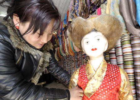 A shopowner shows a traditional children's clothes of Tibetan ethnic group at her shop in Lhasa, capital of southwest China's Tibet Autonomous Region, on Feb. 18, 2009. [Purbu Zhaxi/Xinhua]