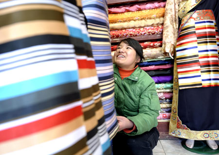  A young lady of Tibetan ethnic group selects traditional clothes of Tibetan ethnic group at a shop in Lhasa, capital of southwest China's Tibet Autonomous Region, on Feb. 18, 2009. [Purbu Zhaxi/Xinhua]