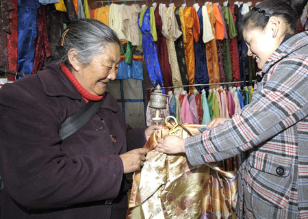 A senior woman of Tibetan ethnic group selects traditional clothes of Tibetan ethnic group at a shop in Lhasa, capital of southwest China's Tibet Autonomous Region, on Feb. 18, 2009. [Purbu Zhaxi/Xinhua]