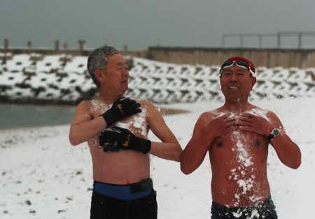 Two Chinese elders wash their body with winter snow prior to swim at an open pool during a snowfall in the costal city of Dalian, northeast China's Liaoning Province, Feb. 18, 2009. Rain and snowfall have helped ease a severe drought in northern and eastern China. [Lv Wenzheng/Xinhua]