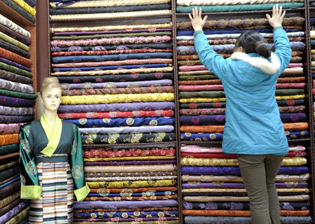 A young lady of Tibetan ethnic group selects cloth making traditional clothes of Tibetan ethnic group at a shop in Lhasa, capital of southwest China's Tibet Autonomous Region, on Feb. 18, 2009. [Purbu Zhaxi/Xinhua]